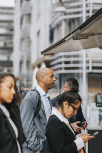 Side view of businessman waiting with colleagues at food truck