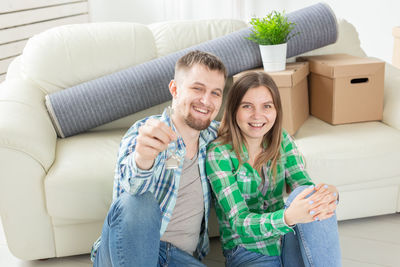 Portrait of couple sitting by sofa at home