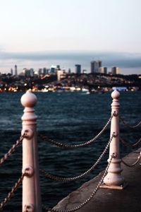 Railing against sea in city during sunset