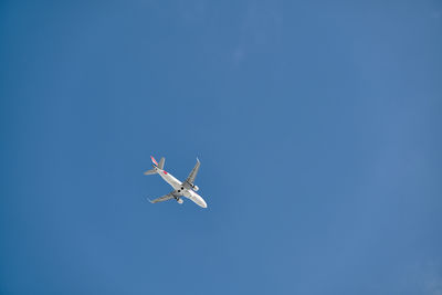 Low angle view of airplane against clear blue sky