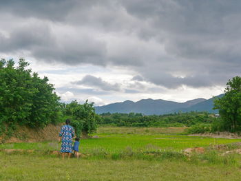 Rear view of person on field against sky