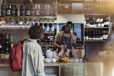 Female customer talking with male owner at delicatessen shop