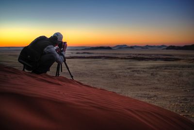 Man photographing at beach against sky