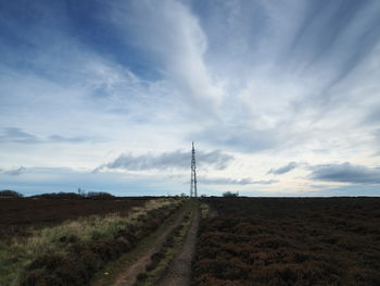 Road amidst field against sky