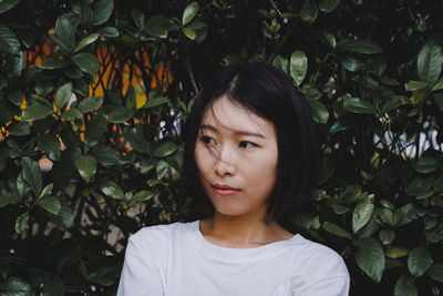 Portrait of young woman standing against plants