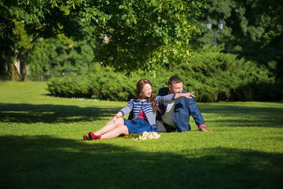Man with woman sitting on grassy field at park
