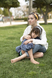 Full length of siblings sitting on field at park