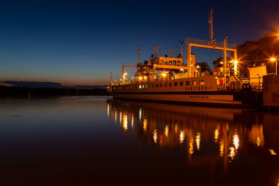 Illuminated pier by sea against sky at night