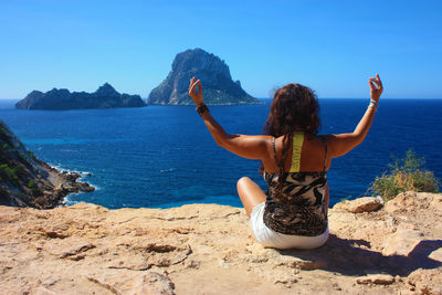 Rear view of woman looking at sea against mountain