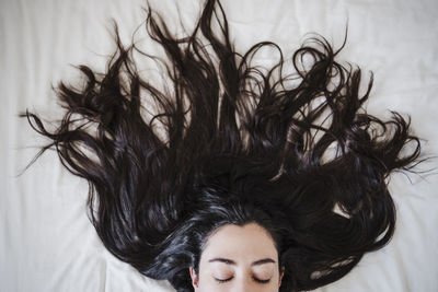 Woman with long hair lying on bed at home