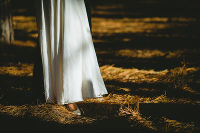 Low section of bride standing on hay