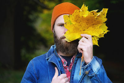 A bearded young man walks in the park in autumn. the guy on the background of the forest - a close