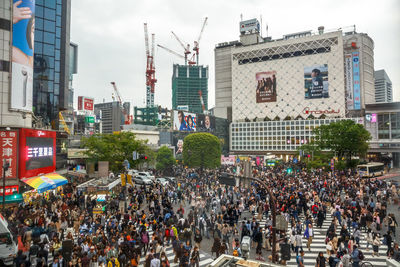 Crowd on city street by buildings against sky