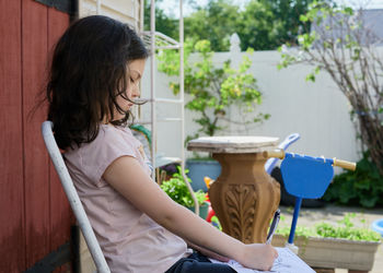 Young girl coloring pictures on a sunny day in the backyard