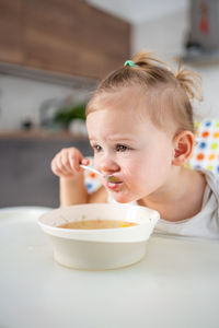 Portrait of cute girl eating food in bowl on table