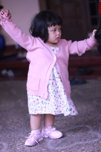 Cute girl standing on pink floor