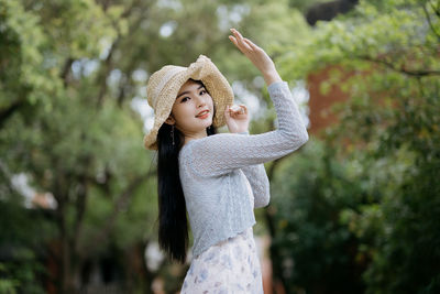 Portrait of young woman standing against trees