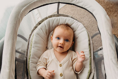 Young baby laying in bassinet and looking up at camera and smiling