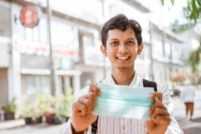 Portrait of smiling man holding while standing against wall