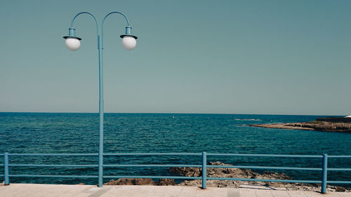 Street light by sea against clear sky