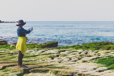 Rear view of woman standing by sea