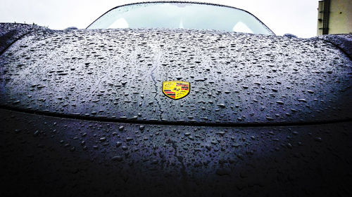 Close-up of wet car against sky