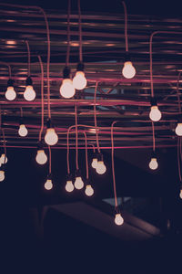 Low angle view of illuminated light bulbs hanging from ceiling