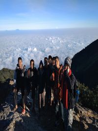 People standing on mountain by sea against sky