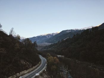 Road leading towards mountains against clear sky