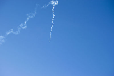 Low angle view of vapor trail against blue sky