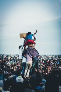 Rear view of people at music concert against sky