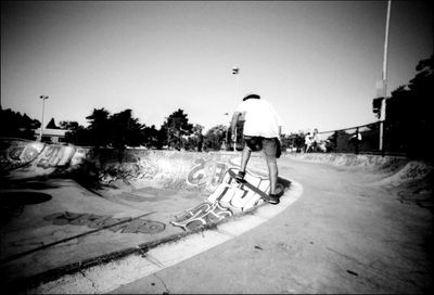 Man skateboarding on street against sky