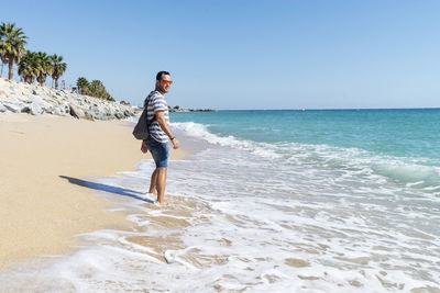 Man standing at beach against clear sky