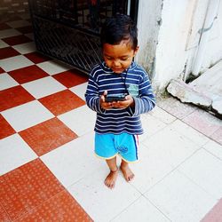 High angle view of boy looking down while standing on tiled floor