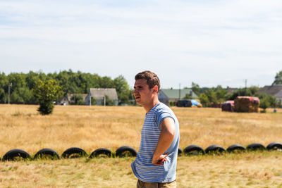 Serious caucasian young man in stripe shirt standing in profile on playground. caucasian portrait.