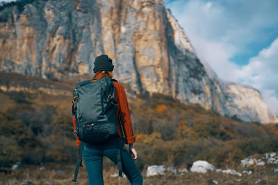 Rear view of man standing on rock against mountain