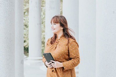 Young woman standing against wall