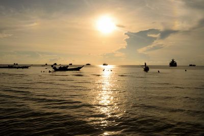 Silhouette boats in sea against sky during sunset