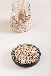 A bowl of shelled sunflower seeds and a jar of seeds on the table. bio and organic food. 