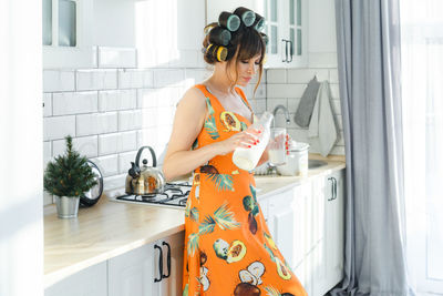 Side view of young woman standing at home