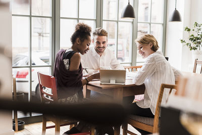 Three young people using tablet in a cafe