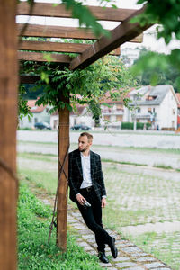 Full length portrait of young man standing against trees