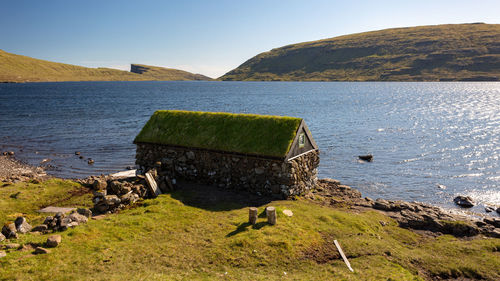 Deck chairs on rocks by sea against sky