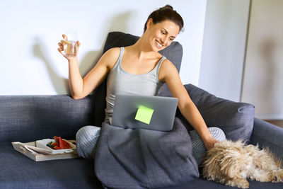 Side view of young woman sitting on sofa at home