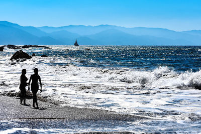 People on sea shore against sky