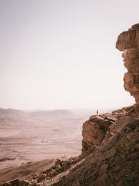 Scenic view of cliff by sea against clear sky