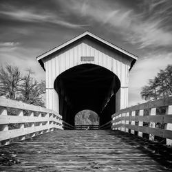 Empty footbridge against cloudy sky