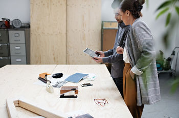 Businessman showing digital tablet to female colleague at table in meeting