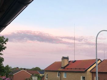 Houses by street against sky during sunset