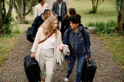 Smiling female professionals talking while walking with colleagues on footpath during business trip